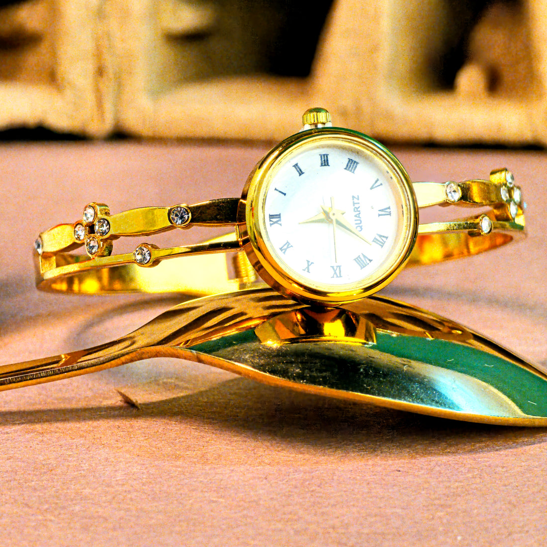Gold bracelet watch with decorative elements on a reflective surface