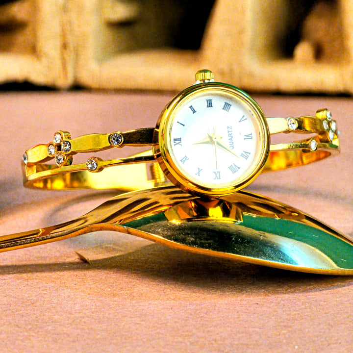 Gold bracelet watch with decorative elements on a reflective surface